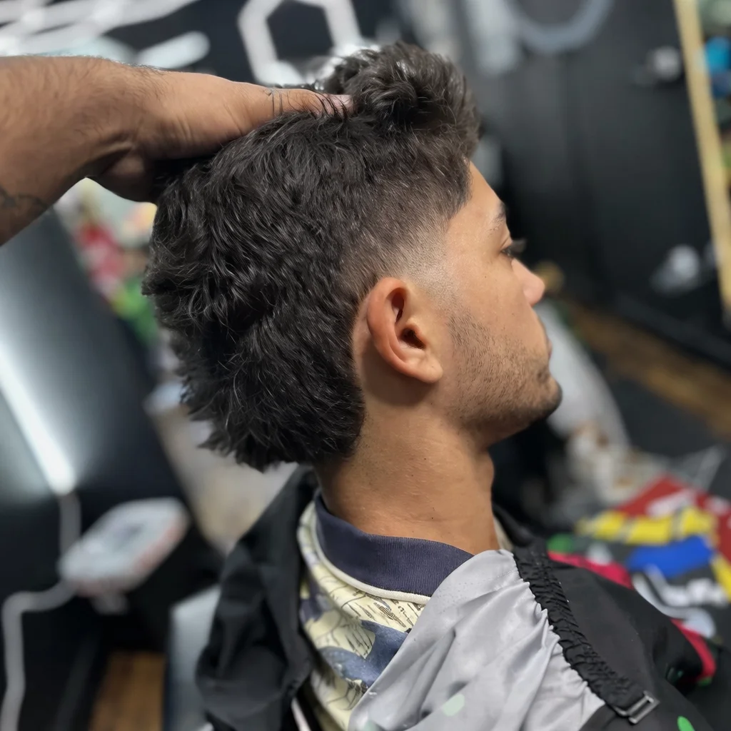 Textured wavy crop with tapered fade, stylist's hand shaping the top